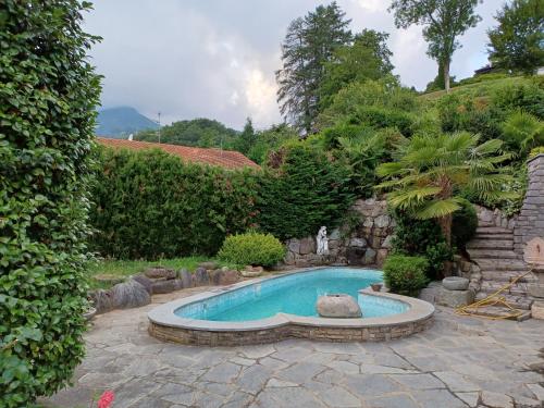 a swimming pool in a garden with a stone wall at Penthouse in the green with private pool and garden in Portula
