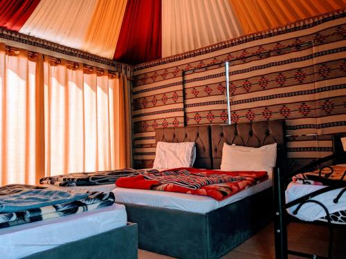 a bedroom with two beds and a wall with curtains at Wadi Rum Camp & Jeep Tour in Wadi Rum