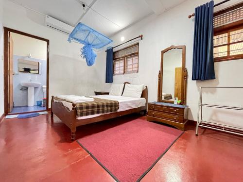 a bedroom with a bed with a mirror and a red rug at SHADEY COTTAGE in Gampola