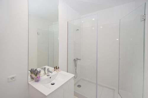 a white bathroom with a sink and a shower at Largo São Domingos by Innapartments in Porto