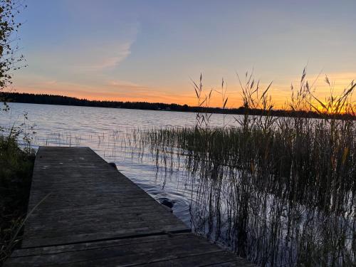 a wooden dock on a lake at sunset at Ferienhaus Anders in Terjärv
