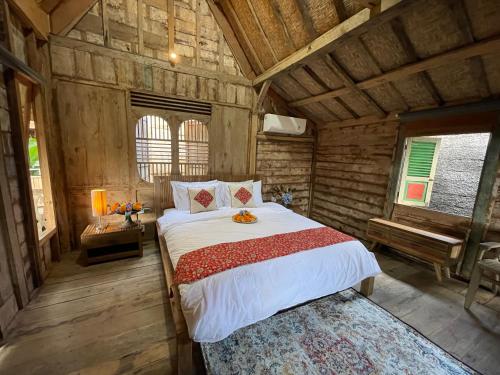 a bedroom with a large bed in a wooden room at Oemah Gebagan 78 Akasha Room B&B in Karangasem