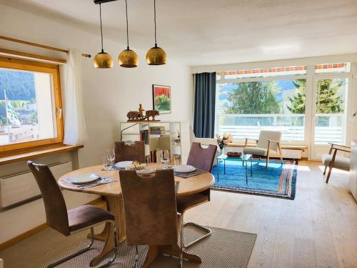una sala da pranzo con tavolo e sedie e un soggiorno di Ferienwohnung Parsenn Peaks Panorama a Davos
