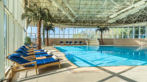 a large swimming pool with lounge chairs and palm trees at Mövenpick Hotel Al Khobar in Al Khobar