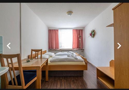 a bedroom with a bed and a table and a window at Hostel im Osterzgebirge in Kurort Altenberg