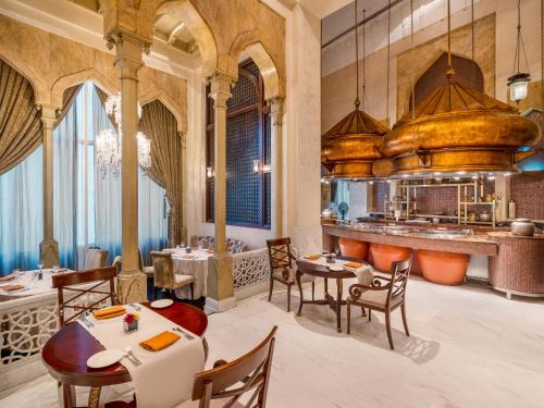 a restaurant with tables and chairs and a kitchen at Mövenpick Hotel Al Khobar in Al Khobar