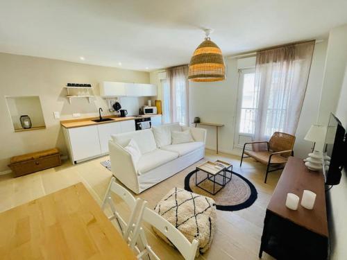 un salon avec un canapé blanc et une cuisine dans l'établissement Maison charmante avec terrasse, 2 chambres, à Marseillan