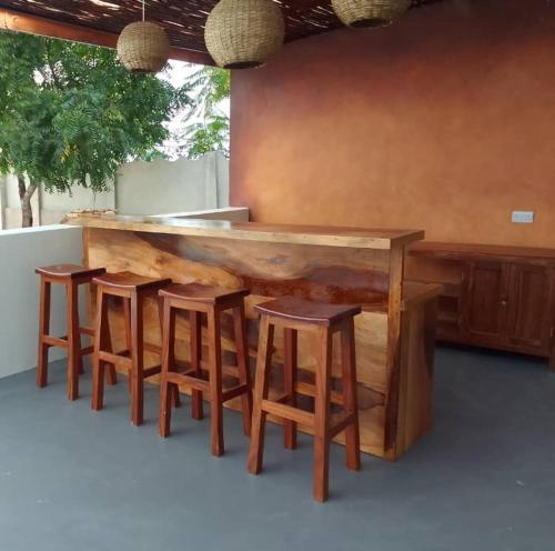 una barra de madera con 4 sillas y una barra en Matumaini Guest House, en Migogoni