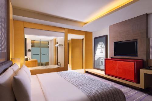 a hotel room with a bed and a flat screen tv at Le Méridien Qingdao l Instagrammable l CBD l Nearby seaside,nearby May 4th Square in Qingdao
