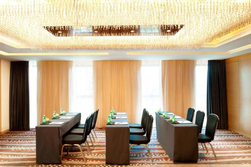 a conference room with long tables and chairs and a chandelier at Le Méridien Qingdao l Instagrammable l CBD l Nearby seaside,nearby May 4th Square in Qingdao