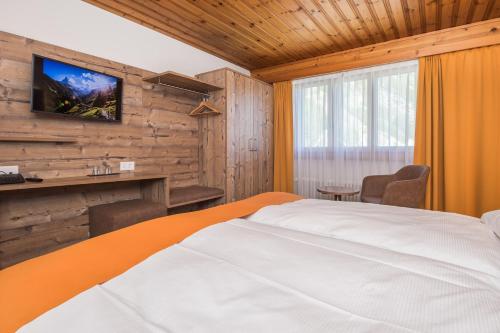 a bedroom with a bed and a tv on a wall at Hotel Taescherhof in Täsch