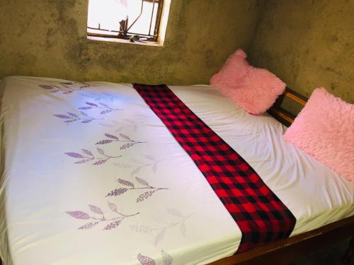 a bed with a plaid blanket and two pink pillows at Kiharas Farm stay in Nairobi