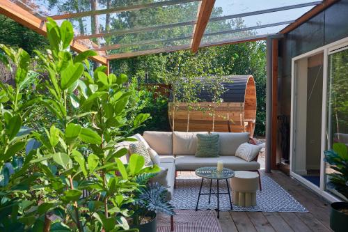 a patio with a couch sitting under a pergola at ZEN-Bungalow no 5 met sauna en hottub in Rheezerveen