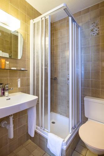 a bathroom with a shower and a sink and a toilet at Hotel Taescherhof in Täsch