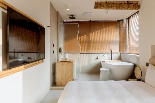 a bathroom with a bed and a tub and a sink at Just Inn Kaohsiung in Kaohsiung