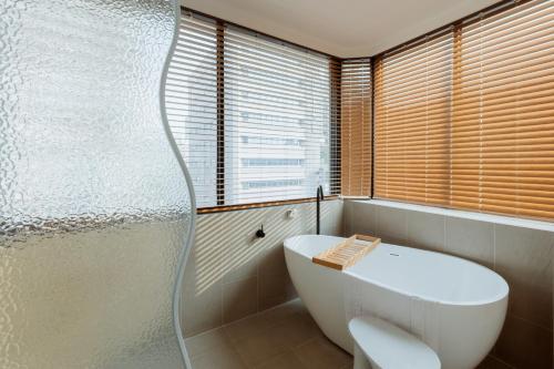 a bathroom with a white tub and a window at Just Inn Kaohsiung in Kaohsiung