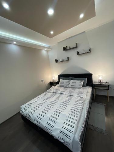 a bedroom with a large white bed with two tables at Apartman Central A&D in Bečej