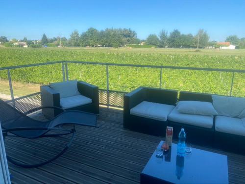 eine Terrasse mit zwei Sofas, einem Tisch und einem Feld in der Unterkunft Les trois Filles in Puybarban
