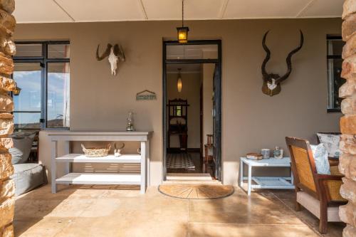 a living room with a white table and antlers on the wall at Tygerfontein Safari Villa in Amakhala Game Reserve