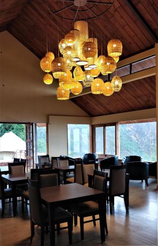 a dining room with tables and chairs and chandeliers at The Bugyal in Kanatal