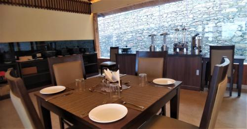 a dining room with a wooden table with white plates at The Bugyal in Kanatal