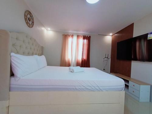 卡巴納端的住宿－6 - Affordable 2-Storey House in Cabanatuan City，卧室配有一张白色大床和一台平面电视。
