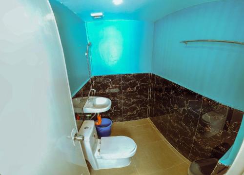 a blue bathroom with a toilet and a sink at Adventourist Inn in Coron