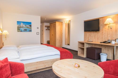 a hotel room with a bed and a table and a tv at Hotel Taescherhof in Täsch