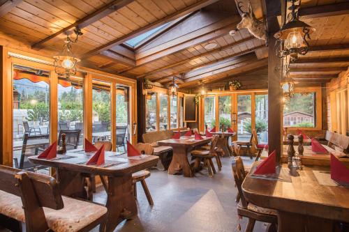 um restaurante com mesas e cadeiras de madeira e janelas em Hotel Taescherhof em Täsch