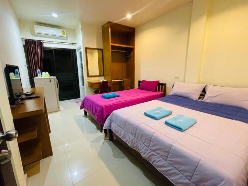 two beds in a room with pink and blue sheets at ดาระณี เพลส in Udon Thani