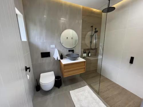 a bathroom with a toilet and a sink and a mirror at Indigo Apartment with Pool 200m to Beach in Palm Cove