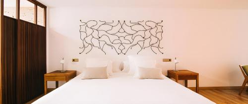 a bedroom with a large white bed with two tables at Hotel Rural Quercus Tierra in Garganta de los Montes