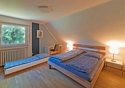 a bedroom with two beds and a desk and a window at Cozy Inn Schladern in Windeck