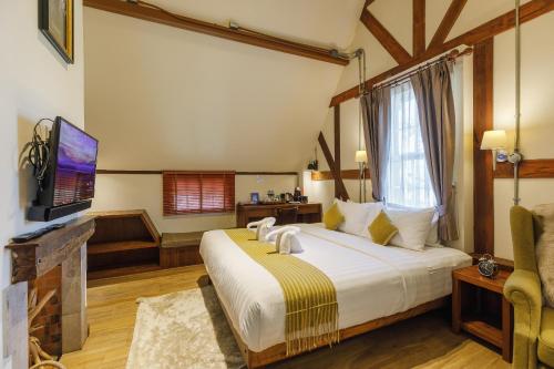 a bedroom with a large bed and a tv at Le Charcoa Hotel in Chiang Mai