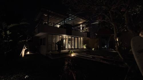 um homem parado fora de uma casa à noite em Villa V Element em Canggu