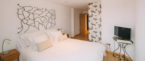 a bedroom with a white bed and a television at Hotel Rural Quercus Tierra in Garganta de los Montes