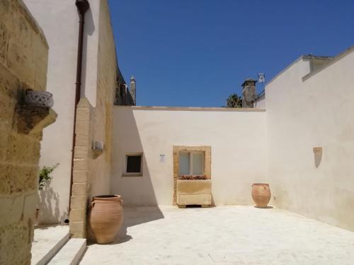 un edificio blanco con dos jarrones en un patio en Dimora Margherita in Salento, en Struda