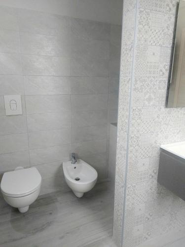 a white bathroom with a toilet and a bidet at Casa Junno in Monte SantʼAngelo