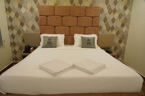 a large white bed with two folded towels on it at Mevid Hotels in Hyderabad