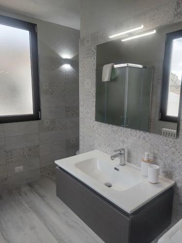 a white bathroom with a sink and a mirror at Casa Junno in Monte SantʼAngelo