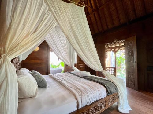 Schlafzimmer mit einem Himmelbett und Moskitonetzen in der Unterkunft Kaiwatu House in Ubud
