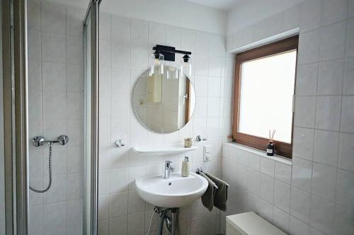 a white bathroom with a sink and a mirror at Friends&Family Veldenz M in Veldenz