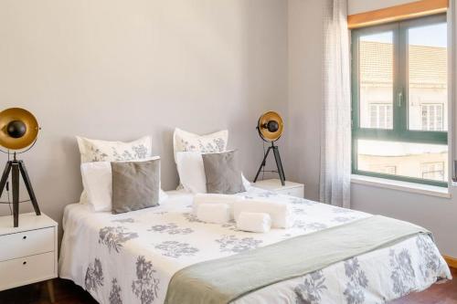 a white bedroom with a large bed with a window at Miguel Torga Gold III in Coimbra