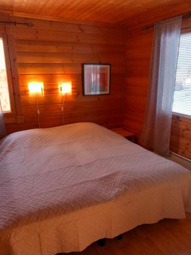 ein Schlafzimmer mit einem weißen Bett in einem Zimmer mit Holzwänden in der Unterkunft Himos, KOIVULA 25, center area in Jämsä