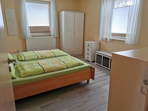 1 dormitorio pequeño con 1 cama y 2 ventanas en Ferienwohnungen Harmonie und Bergblick, en Crostau