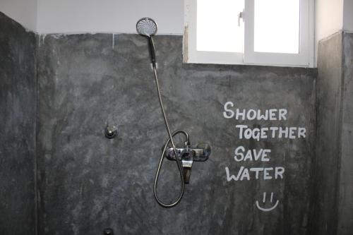 a shower in a bathroom with the words shower together save water at Sun & Moon Hostel in Mirissa