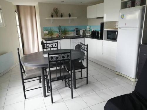 a kitchen with a table and chairs and a refrigerator at Gîte Bin Benaise draps et serviettes compris in Pamproux