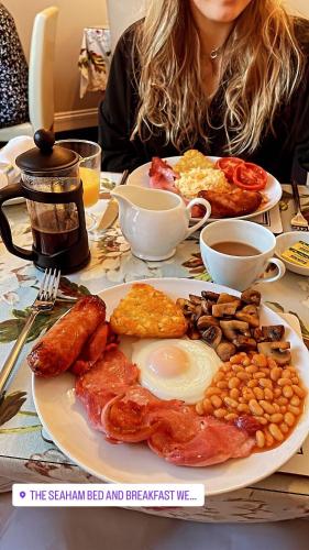 a woman sitting at a table with a plate of breakfast food at Seaham in Weymouth