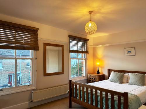 - une chambre avec un lit et 2 fenêtres dans l'établissement Daisy’s Place in London, à Londres