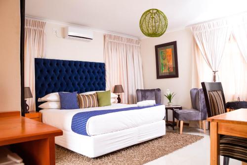 1 dormitorio con 1 cama grande y cabecero azul en Olive Country Lodge - Eswatini, en Ngwempisi